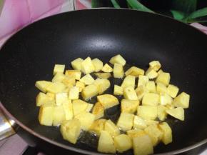 不粘锅加少量油倒入土豆丁中火煎至表皮金黄捞出备用，煎过的土豆炖起来不容易烂