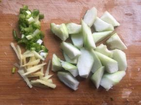将丝瓜削皮洗净，然后切小滚刀块，大块难熟，烹饪时间长且不易入味；然后再将生姜、香葱切碎即可；