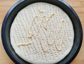 饼底挤上香甜口味的沙拉酱，用勺子涂抹均匀。