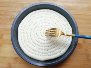 擀成和披萨盘一般大小的面饼，放入披萨盘里，用叉子扎满小孔。