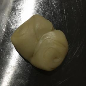 静至好的酥皮从中间按压出勒痕。用手掌将两端按压直中心。