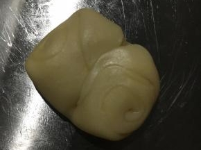 静至好的酥皮从中间按压出勒痕。用手掌将两端按压直中心。