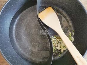 首先把葱绿和葱白切好，我备了鸳鸯锅，一边倒入适量食用油，升温后放入蒜片和葱白炒香。