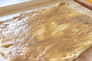 玉米面片那面，涂抹芝麻酱，注意边角处也涂抹。再制作芝麻酱抹面前，要把内部的酱和芝麻油搅匀，让芝麻酱融合了芝麻油，取出大约55克芝麻酱再放入少量的面粉，搅匀，状态是略浓稠，放到面皮上可以用刮刀推开。