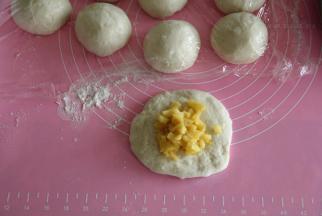 面团取出按压排气，然后平均分割成12个，其实可以分14-16个，我做的苹果餐包略大只。面团用右手反C状握住逆时针滚圆，盖保鲜膜醒10分钟。然后取一醒发好的面团，按扁，擀成圆形，放上馅料。馅料根据自己喜好放，可以多放一点点，也可以少放一点，如果想多放就需要将馅料部分翻倍操作！