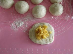 面团取出按压排气，然后平均分割成12个，其实可以分14-16个，我做的苹果餐包略大只。面团用右手反C状握住逆时针滚圆，盖保鲜膜醒10分钟。然后取一醒发好的面团，按扁，擀成圆形，放上馅料。馅料根据自己喜好放，可以多放一点点，也可以少放一点，如果想多放就需要将馅料部分翻倍操作！