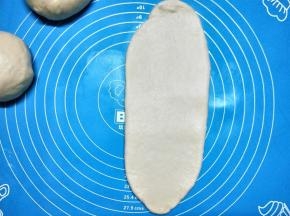 取一个松驰好的小面团，用擀面杖擀成长舌形，从上往下卷起