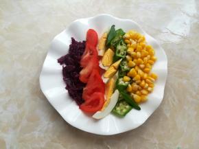 盘子里放上玉米粒、秋葵、番茄和鸡蛋，加上紫椰菜