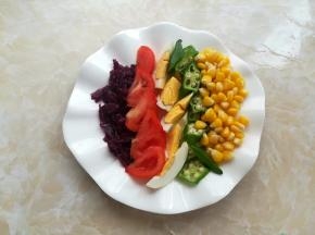 盘子里放上玉米粒、秋葵、番茄和鸡蛋，加上紫椰菜