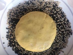 放入黑白芝麻的平碗中，轻轻按压，使芝麻粘紧实些，避免芝麻容易掉；