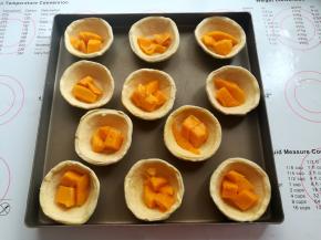 每个蛋挞皮里放入2-3小块芒果肉