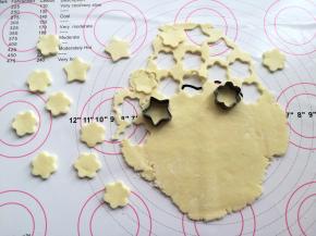 用最小号的花朵和五角星的饼干模具在奶粉面团上印出奶片的形状，边角部分重新揉成一团，再擀开印出奶片，反复操作，一直到全部做成奶片，家里没有饼干模具可以直接用圆形的瓶盖子