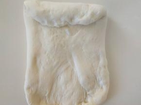 １１、将面团分成２块，用手压扁，翻面后从上往下卷起，不用卷太多。