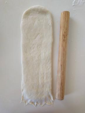 １３、将松弛好的面团擀开，翻面，压薄底边，长度与擀面杖差不多长就可以。