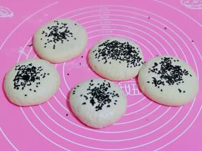 每个饼胚上沾少许水，再撒上黑芝麻，用掌心轻轻按一下，这样芝麻不容易掉。