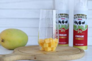 芒果去皮切成小方块，一半放入玻璃杯内。