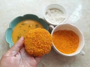 把土豆团按扁，先裹一层面粉，再裹上蛋液，最后沾上适量的黄色面包糠，两面都要沾上