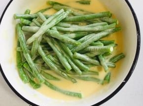 把豆角放入调好的糊中，让每个豆角都均匀的裹满糊糊。