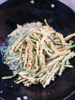 炸好的豆角再次复炸一遍，捞出沥干油分备用。