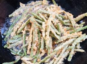 炸好的豆角再次复炸一遍，捞出沥干油分备用。