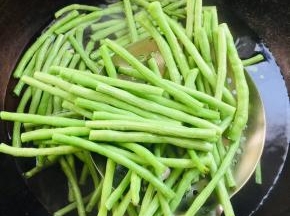 水烧开放入豆角焯水1分钟捞出，放在冷水中投凉沥干水分备用。