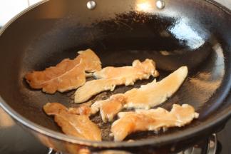 锅烧热，放入少许的油，将油把锅润一下，放入腌制好的鸡肉片。

