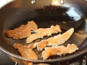 锅烧热，放入少许的油，将油把锅润一下，放入腌制好的鸡肉片。

