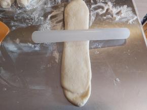 再取一个擀卷的面团，再次擀成长舌状，不要来回擀，在中间固定，然后用擀面杖朝两边拉长，长度要比之前长一些。