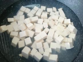 锅内加水烧开，放一点点盐和几滴食用油，下入豆腐块焯水，捞出控一下水分备用。