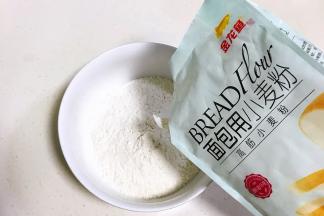 大碗内倒入金龙鱼面包用小麦粉和盐，混合拌匀。