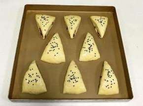 司康摆入不粘烤盘，表面刷上全蛋液，撒上黑芝麻。