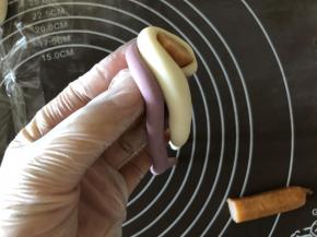 把两个颜色的面条合并在一起，从香肠的切面开始，围一圈，如图把面条的起头藏起来。