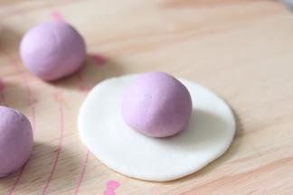 白色的擀成圆片形状，包入紫薯团，像包汤圆一样，收口捏紧。