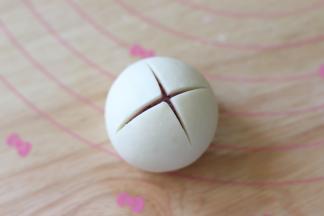 用刀在顶部划开十字，划的程度以看到内部的紫薯面团为准，如果想要成品开口的程度大一些，可以在划的长一点。