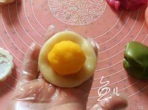 分成25克一个小面团，搓成小圆球压扁，放上奶黄馅