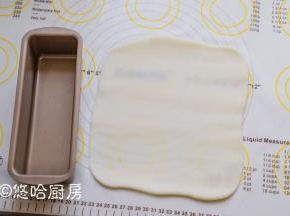 把水晶皮平均分成2块，案板上撒一点冰皮粉，将水晶皮擀开和旁边的磅蛋糕模具一样长。