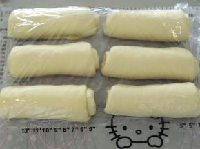 取一小份面团，擀成牛舌状，翻面，从上往下卷好，盖保鲜膜松弛15分钟。