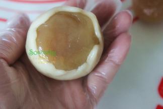 取15克的月饼皮揉搓光滑，放在手掌心上压扁，把莲蓉蛋黄馅放在月饼皮上，推面皮，慢慢收口。