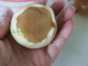 取15克的月饼皮揉搓光滑，放在手掌心上压扁，把莲蓉蛋黄馅放在月饼皮上，推面皮，慢慢收口。