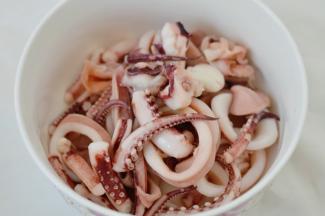 之后将鱿鱼捞出，洋葱切条，红辣椒跟绿辣椒分切成宽条