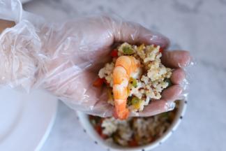 取一小份彩椒藜麦饭放在手心，中间放入虾。