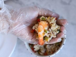 取一小份彩椒藜麦饭放在手心，中间放入虾。