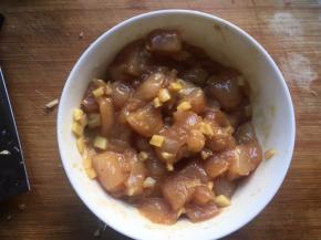 将鸡丁和姜碎放入碗中，再倒入2勺啤酒、2勺生抽、半勺老抽、1勺糖、适量淀粉，用筷子沿着一个方向搅拌均匀，腌制15分钟以上；