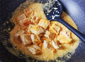 接着把煎制好的豆腐块倒入，裹上咸蛋黄，撒入点生抽提鲜。