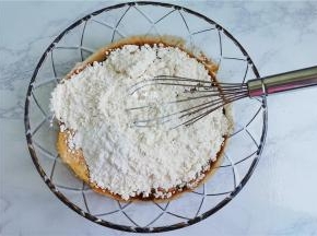 接着把低筋面粉和泡打粉倒入红糖水中。