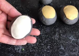 把黄面团和白面团擀成小一号的椭圆面皮，贴在黑色椭圆面团上