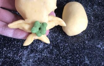 用绿色面团做一朵小花，贴在肚子中间