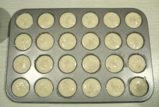 提起裱花袋，拧紧袋口。将裱花袋剪小口，挤入刷好脆皮糊的模具中。9分满，撒入白芝麻。如果没有白芝麻，黑芝麻也可以。