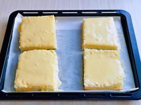 将吐司摆入垫有油纸的烤盘中，用小勺盛入芝士奶油糊在每片吐司上，用小勺背面抹均匀。