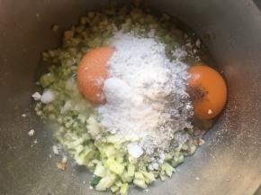 往麦片中磕入鸡蛋，倒入西葫芦丁，调入糖、盐、胡椒粉；
